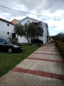 um carro estacionado em frente a uma casa branca em Apartments with a parking space Kraj, Pasman - 8213 em Tkon