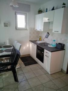 uma cozinha com armários brancos, um lavatório e uma mesa em Apartments with a parking space Kraj, Pasman - 8213 em Tkon