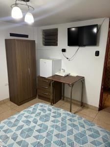 ein Büro mit einem Schreibtisch und einem TV an der Wand in der Unterkunft HOTEL SAN VICENTE in Cajamarca