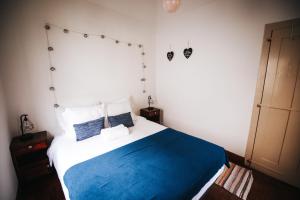 een slaapkamer met een bed met blauwe en witte lakens bij Casa da Avo Rosa in São Vicente