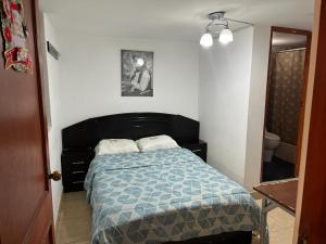 a bedroom with a bed with a blue comforter at HOTEL SAN VICENTE in Cajamarca
