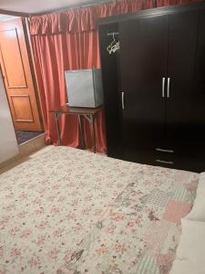 カハマルカにあるHOTEL SAN VICENTEのベッドルーム1室(ベッド1台、テーブル、キャビネット付)
