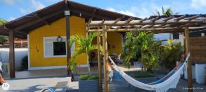 une maison jaune avec un hamac devant elle dans l'établissement Casa na Ilha da Crôa/Barra de Santo Antônio, à Barra de Santo Antônio