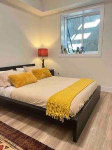 Un dormitorio con una cama con almohadas amarillas y una ventana en Grand Boulevard Guest Suite, en North Vancouver