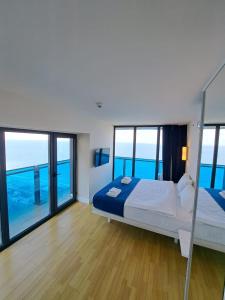 a bedroom with a bed and large windows at ORBI SITY BATUMI in Batumi