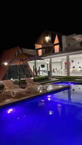 basen z krzesłami i parasolem w nocy w obiekcie Villa Suíça, Chalé Mezanino w mieście Tianguá