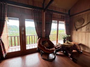 um quarto com uma cadeira e uma varanda com janelas em Trốn Homestay, Cao Bằng em Cao Bang