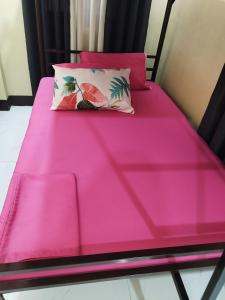 Una cama rosa con una almohada encima. en Jumong's Transient Inn, en Bantay