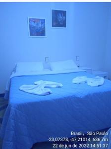 um quarto com uma cama azul com duas toalhas em Acomodações Anfitriã em Indaiatuba