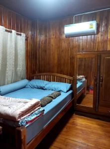 a bedroom with two beds in a wooden wall at ครัวป่าตันแอนด์โฮมสเตย์ 