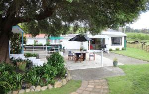 un patio con una mesa y una sombrilla frente a una casa en The Cowshed en Whitianga