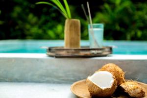 a coconut on a plate on a table with a drink at Coco Bungo - Beachside Bungalow #3 in Santa Teresa Beach