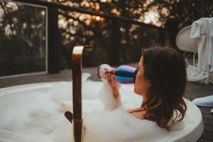 a woman in a bath tub drinking from at Domo Supernova by @highlowstays in Gramado