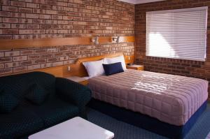 1 dormitorio con 1 cama, 1 silla y 1 sofá en Mid Town Inn Narrabri, en Narrabri