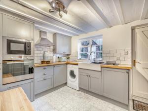 a kitchen with white cabinets and a washer and dryer at The Wild Cherry Tree Retreat in Ironbridge