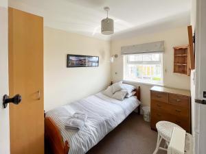 a bedroom with a bed and a desk and a window at Coastguard Cottage in Downderry