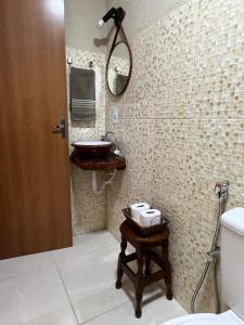 La salle de bains est pourvue d'un lavabo, d'un miroir et de toilettes. dans l'établissement Reserva do Bosque Hospedaria e Natureza, à Ibicoara