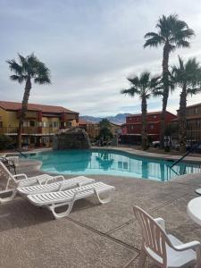 a swimming pool with lounge chairs and palm trees at Mesquite Magic in Mesquite