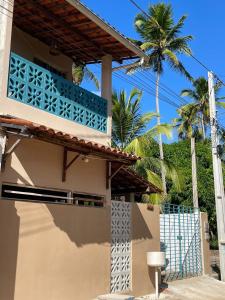 dom z niebieskim balkonem i palmami w obiekcie Casas Aconchego do Mar w mieście Japaratinga