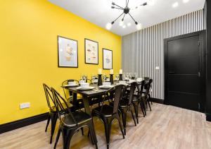 uma sala de jantar com uma mesa longa e cadeiras em Bright & Colourful House - Best for a Large Groups em Londres