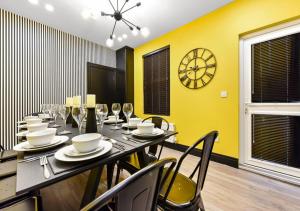 una sala da pranzo con tavolo, sedie e orologio di Bright & Colourful House - Best for a Large Groups a Londra Altre 22 foto