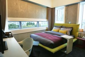 a bedroom with a bed and a desk and windows at Hotel Cocomo in Seoul