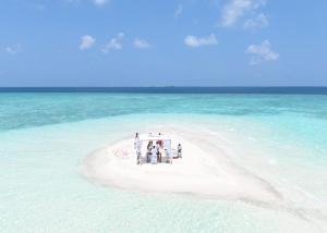 a group of people standing on a small island in the ocean at PrivHotel - Himandhoo in Himandhoo 