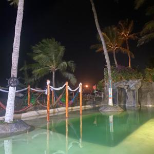 a pool at a resort at night with palm trees at Pousada Villa Kite Flecheiras in Trairi