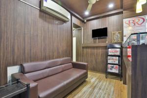 una sala de espera con sofá de cuero y TV en OYO Hotel Sree Balaji Residency, en Bodakdev