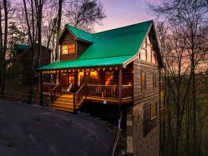 a log cabin with a green roof and a porch at Updated Serene Mtn Cabin, theater rm & popcorn! in Sevierville