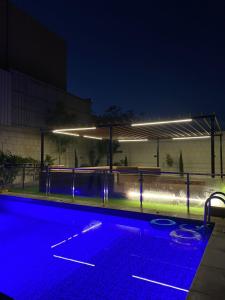 uma piscina vazia à noite com luzes azuis em منتجع رويال لاند em Ash Shuwaybiţ