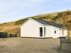 a white building with a hill in the background at Watersreach in Collieston