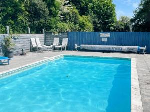 a blue swimming pool with chairs and a fence at Uk45543-the Threshing Barn in Sticklepath