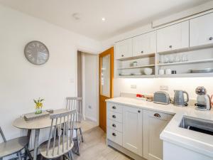 una cocina con armarios blancos y una mesa con sillas. en Wharfedale Cottage, en Harrogate