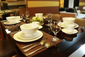 a wooden table with white dishes and wine glasses at BSA Twin Towers in Manila