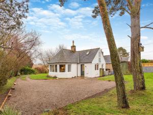 a white house with a driveway in front of it at East Tarrel Cottage in Portmahomack