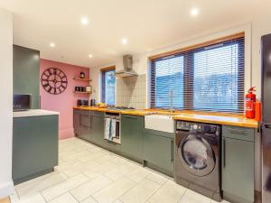 a kitchen with green cabinets and a washer and dryer at East Tarrel Cottage in Portmahomack