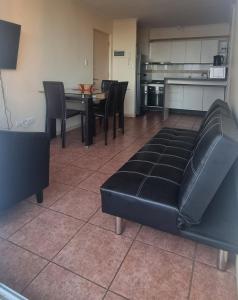 a living room with a black leather couch and a table at Arriendo departamento La Serena, sector el faro in La Serena