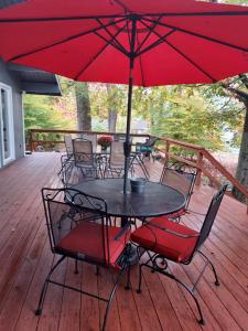 a table and chairs with an umbrella on a deck at Chic and Stylish home Hot tub,4 bedrooms, game movie room, firepit, arcades, playground on site 2 min walk from pool and lake in Tobyhanna