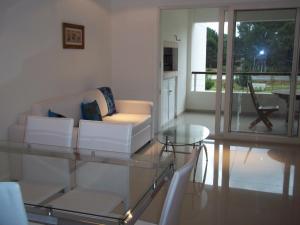 uma sala de estar com um sofá branco e uma mesa de vidro em Green Park Punta del Este em Punta del Este