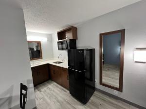 a kitchen with a black refrigerator and a sink at HomeTowne Studios by Red Roof Florence, KY-Cincinnati Airport in Florence