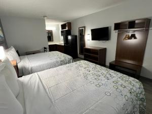 a hotel room with two beds and a flat screen tv at HomeTowne Studios by Red Roof Florence, KY-Cincinnati Airport in Florence