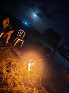un grupo de personas sentadas alrededor de un fuego por la noche en habitación frente al mar, en Mayapo