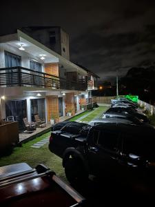 Una fila de autos estacionados fuera de un edificio por la noche en Pousada Vielas do Rosa - centrinho da praia do rosa en Praia do Rosa