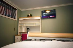 - une chambre avec un lit et une télévision murale dans l'établissement Cozy private bedroom and living room in our home, à Gatineau