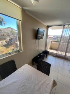 um quarto com uma cama, uma televisão e uma janela em Departamento en Huasco, Atacama em Huasco