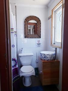 a bathroom with a toilet and a sink and a mirror at Hostal Arrayan in Valdivia