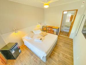 a bedroom with a white bed and a television at Pousada Ar da Montanha in Serra Negra