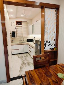 eine Küche mit weißen Schränken, einem Tisch und einem Kühlschrank in der Unterkunft Aura Home Stay in Mohali