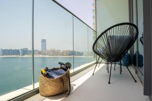 un panier et une chaise sur un balcon avec vue sur l'eau dans l'établissement Veluxa - Luxe Beach Vista 2 Bed, à Dubaï